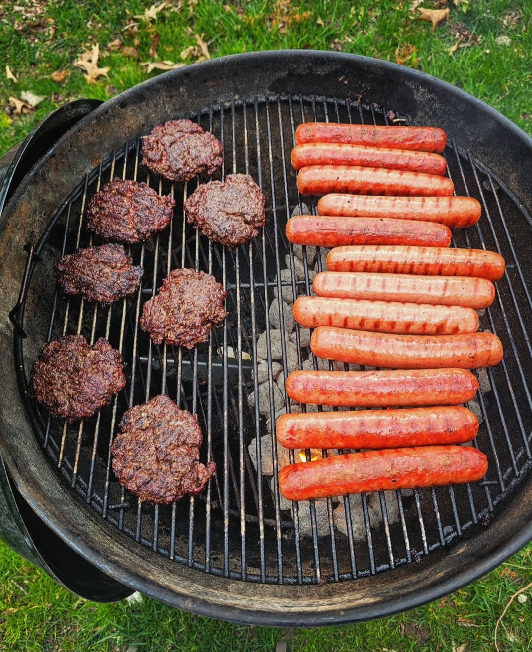 hotdogs and Hamburgers cooking on a coal grill