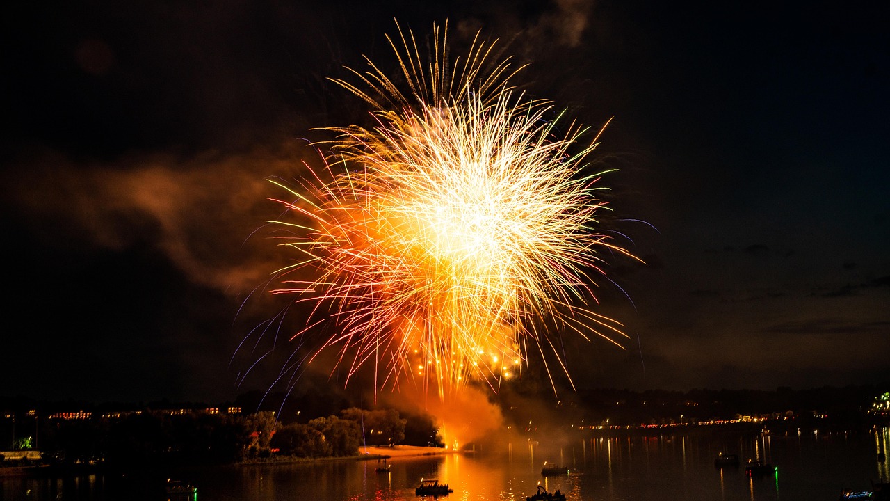 one orange firework exploding above a body of water
